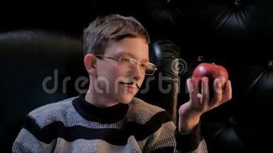 一个戴眼镜、留着八字胡的年轻人坐在黑色扶手椅上，拿起一个红苹果。一个男人脸上悲伤的表情